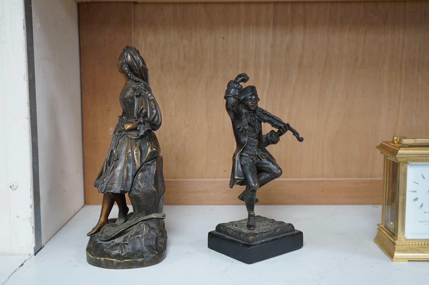 A small bronze figure of a male violinist and another bronze female figure with a lute against a rock, tallest 23cm high